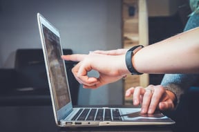 two hands pointing at a computer screen